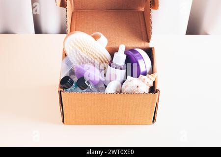 Beauty-, Spa- und Hautpflegeprodukte in Packungen in Karton auf beigefarbenem Tisch. Kosmetikflasche mit Öl oder Serum, Gesichtsmaske, Shampoo, Körperseife. Stockfoto