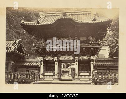 Yōmeimon-Tor am Nikkō Tōshō-gū-Schrein. Unbekannt, Fotograf der 1850er–1890er Jahre Blick auf das Yomeimon-Tor am Nikko Tosho-gu-Schrein. Zwei Mönche stehen oben auf der Treppe vor dem aufwendig geschmückten Tor. Einer der Mönche steht mit dem Rücken zur Kamera unter dem Bogengang, während der andere mit Blick auf die Kamera an der Spitze der Stufen steht und mit einer Hand am Geländer festhält. Zwei Statuen flankieren den rechteckigen Bogen, der von aufwendigen und detaillierten Schnitzereien und Relieffiguren umgeben ist. Stockfoto