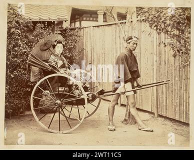 Japanerin in einer Rikscha. Unbekannt, Fotograf der 1850er–1890er Jahre Ansicht eines Mannes, der zwischen den Stangen einer Rikscha steht und sie hält, während er mit einem gestreckten Bein vor sich steht und seinen Fuß sanft zeigt. Eine Frau sitzt in der Rikscha in traditioneller japanischer Kleidung und hält einen offenen Sonnenschirm oder einen Sonnenschirm aus Ölpapier über die Schulter, während sie in die Kamera schaut. Stockfoto