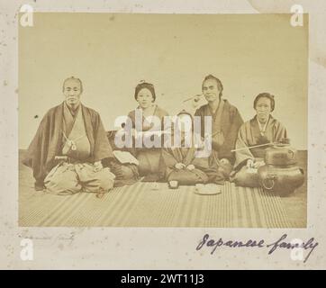 Japanische Familie. Unbekannt, Fotograf 1860er–1870er Jahre Gruppenporträt von zwei Männern, zwei Frauen und einem Kind in traditionellen japanischen Kleidungsstücken. Mehrere Tassen und Utensilien, die normalerweise bei traditionellen japanischen Teezeremonien verwendet werden, sind ebenfalls zu sehen, darunter ein „Fur“ oder ein tragbarer Brazier im unteren rechten Bildbereich. (Recto, Mount) Mitte links, unter Bild, Bleistift: 'Japanische Familie'; Mitte rechts, unter Bild, in lila Tinte: 'Japanische Familie'; Stockfoto