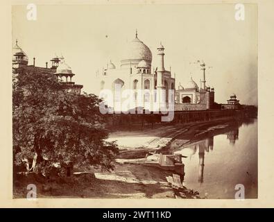 Taj Mahal am Ufer des Yamuna River. John Edward Saché, Fotograf (preußisch oder britisch, geb. Preußen, 1824–1882) aus den 1850er–1890er Jahren Blick auf den Taj Mahal und den Yamuna-Fluss vom Ufer östlich des berühmten Mausoleums. Zwei Figuren sind zu sehen, wie sie Kleidung waschen und sie am Flussufer auslegen, direkt neben einem Gheat, einer kurzen Steintreppe, die zum Wasser führt, im Vordergrund. Die Kuppeln des Mihman Khana sind über den Bäumen auf der linken Seite des Bildes zu sehen. Stockfoto