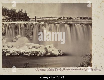 Horse Shoe Falls, Kanada-Seite. Unbekannt, Fotograf 1860s–1873 Blick auf die Horseshoe Falls, Teil der Niagarafälle, im Winter. Die Terrapin Bridge und der Turm ragt oben links auf dem Bild von Goat Island aus. Die Felsen am Fuße des Wasserfalls sind mit Schnee und Eiszapfen bedeckt. (Recto, Mount) unten links, unten Bild, in Bleistift: „Horse Shoe Falls [sic] Canada Side“; unten rechts, unten Bild, in lila Tinte: „Horse Shoe Falls, Canada Side - Winter View“; Stockfoto