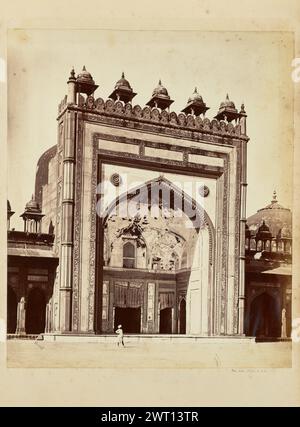 Jama Masjid, Fatehpur Sikri. Thomas A. Rust, Fotograf (Englisch, 1841 - 1904) 1870er Jahre Blick auf eines der Tore des Jama Masjid in Fatehpur Sikri vom Innenhof. Der Eingang ist mit einem Iwan umgeben, der von geometrischen Mustern geschnitzt ist, und fünf Chhatri oder kleine Pavillons säumen die Spitze. Ein Mann steht vor dem Tor mit einer Hand auf der Hüfte. Stockfoto