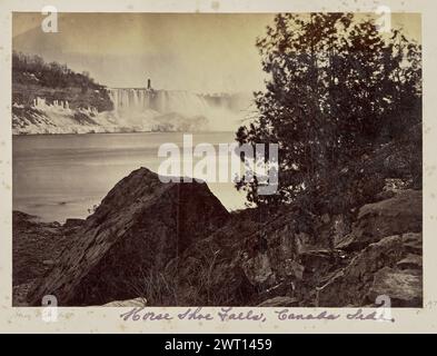 Pferdeschuhfall. Unbekannt, Fotograf 1860s–1873 Blick auf die Horseshoe Falls, Teil der Niagarafälle, im Winter. Die Terrapin Bridge und der Turm ragt oben links auf dem Bild von Goat Island aus. Die Felsen am Fuße des Wasserfalls sind mit Schnee und Eis bedeckt, die teilweise von einigen Felsen und Sträuchern im Vordergrund verdeckt werden. (Recto, Mount) Mitte links, unten Bild, Bleistift: 'Horse Shoe Fall [sic]'; Mitte, unten Bild, lila Tinte: 'Horse Shoe Falls, Canada Side'; Mitte rechts, unten Bild, Bleistift: '1'; Stockfoto