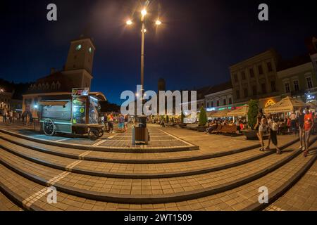 BRASOV, RUMÄNIEN - 11. JULI 2020: Nächtlicher Blick auf den Ratsplatz mit Touristen, im historischen Zentrum der Stadt. Es ist umgeben von 18. Stockfoto