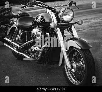 Schwarzes Honda Shadow Cruiser-Motorrad, das am Straßenrand geparkt ist. Motorrad mit verchromtem Motor. Das Motorrad Honda Shadow B Stockfoto