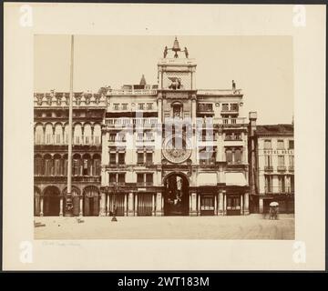 St. Marks Uhrturm. Unbekannt, Fotograf ca. 1865–1880 Ein mehrstöckiges Gebäude mit einem großen Uhrturm in der Mitte. In der Mitte des Turms befindet sich ein in 24 Segmente gegliedertes Zifferblatt. Auf dem Turm befindet sich eine Statue eines geflügelten Löwen, direkt unter zwei Skulpturen von Figuren, die eine Glocke läuten. (Recto, Mount) unten links, Bleistift: "Uhrturm - Venedig"; Stockfoto
