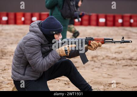 Ziviler ukrainischer Mann, der trainiert, mit einem AK auf einem Militärgelände zu schießen. Kiew - 27. Januar 2024 Stockfoto