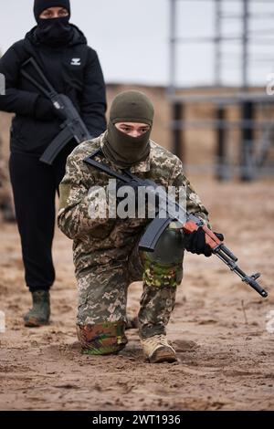 Ukrainische Rekrutenausbildung mit einer Waffe auf einem militärischen Polygon. Ein junger Mann, der das Gewehr überreicht. Kiew - 27. Januar 2024 Stockfoto