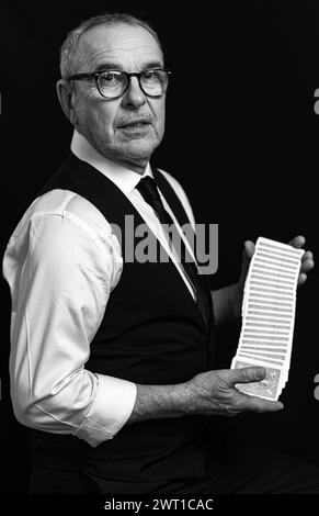 Ein Zauberer manipuliert Spielkarten, um einen Zaubertrick auszuführen. Als klassischer Gentleman verkleidet, spielt er Magie, Illusionen und Poker. Stockfoto