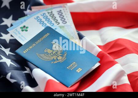 Blauer Indonesien Pass und Geld auf der US-Nationalflagge Hintergrund Nahaufnahme. Tourismus und Diplomatie Stockfoto