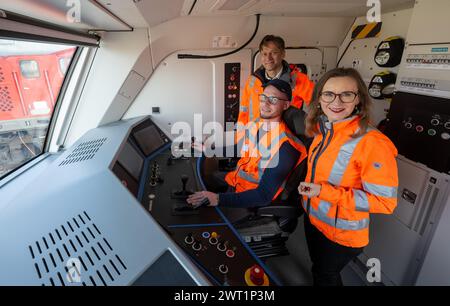 15. März 2024, Sachsen-Anhalt, Halle (Saale): Michael Peter (l-r), Geschäftsführer Siemens Mobility, Sebastian Schröder, Triebwagenfahrer, und Sigrid Nikutta, CEO von DB Cargo, sprechen im Führerhaus einer neuen Hybridlokomotive. Künftig wird die neue Generation von Lokomotiven rein elektrisch auf elektrifizierten Gleisabschnitten fahren, während auf Abschnitten ohne Freileitungen ohne Wechsel der Lokomotiven auf konventionellen Antrieb umgeschaltet werden kann. Die Hybridlokomotiven, die Vectron Dual Mode Light genannt werden, werden vom Bahnanbieter Siemens Mobility hergestellt. Wenn die Lokomotive schlecht ist Stockfoto