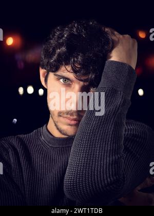 Ein Mann in einem schwarzen Pullover mit der Hand auf dem Kopf Stockfoto