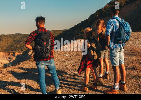 Gruppe von vier Freunden, die gemeinsam bei Sonnenuntergang durch die Landschaft wandern. Stockfoto
