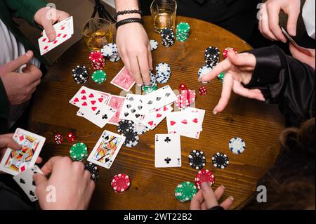 Iwano-Frankiwsk, Ukraine 23. Februar 2024: Fünf junge Leute spielen Poker und trinken Jack daniels Whiskey, Team im Friseurladen. Stockfoto