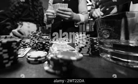 Iwano-Frankiwsk, Ukraine 23. Februar 2024: Fünf junge Leute spielen Poker und trinken Jack daniels Whiskey, Team im Friseurladen. Stockfoto