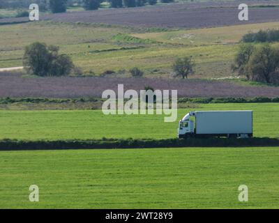 Ein Lieferwagen fährt durch grüne Felder auf dem Land Stockfoto