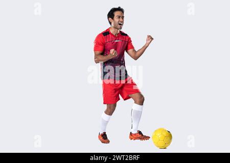 Junge Fußballspieler zeigen Spannung und Freude, nachdem sie gewonnen und erfolgreich gefeiert haben, stehen im Studio auf weißem Hintergrund. Stockfoto