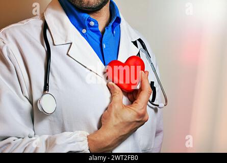 Man Doctor sieht ein rotes Herz. Dieses Bild kann verwendet werden, um Liebe, Sorgfalt oder Unterstützung zu vermitteln. Es ist für verschiedene Projekte und Designs geeignet. Stockfoto