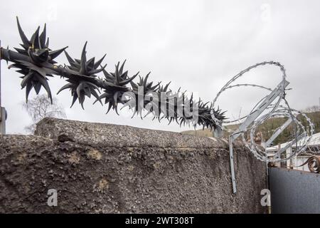 Anti-Wall-Klettern rotierende Sicherheitsspitzen und Rasierdraht als Abschreckung für Kriminalität (scharfe Widerhaken auf Sicherheitsdrehern). Schutz von Eigentum. Stockfoto