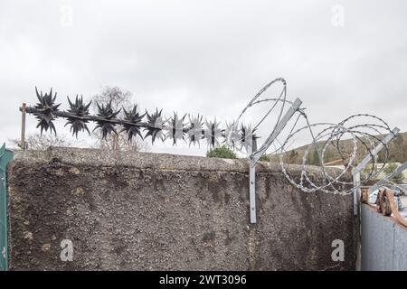 Anti-Wall-Klettern rotierende Sicherheitsspitzen und Rasierdraht als Abschreckung für Kriminalität (scharfe Widerhaken auf Sicherheitsdrehern). Schutz von Eigentum. Stockfoto