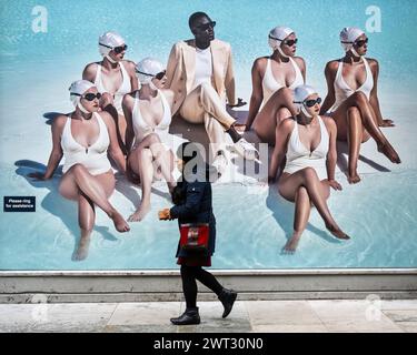 London, Großbritannien. 15. März 2024. Eine Frau schickt ein Poster vor einem Designer-Bekleidungsgeschäft für Männer in der Nähe der Saville Row. Sean Dixon, Geschäftsführer des maßgeschneiderten Schneiders Richard James von Savile Row, sagte, dass britische Läden derzeit an Modehäuser in Paris und Mailand verlieren, und gehört zu mehreren in der Geschäftswelt, die die Abschaffung der so genannten Touristensteuer fordern. Die Regierung hat vor drei Jahren das mehrwertsteuerfreie Einkaufen für Touristen abgeschafft, was insbesondere Luxuseinzelhändler betrifft, die auf wohlhabende Touristen angewiesen sind. Quelle: Stephen Chung / Alamy Live News Stockfoto