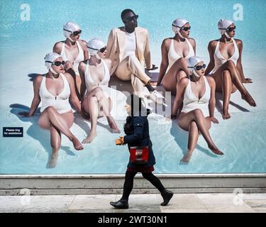 London, Großbritannien. 15. März 2024. Eine Frau schickt ein Poster vor einem Designer-Bekleidungsgeschäft für Männer in der Nähe der Saville Row. Sean Dixon, Geschäftsführer des maßgeschneiderten Schneiders Richard James von Savile Row, sagte, dass britische Läden derzeit an Modehäuser in Paris und Mailand verlieren, und gehört zu mehreren in der Geschäftswelt, die die Abschaffung der so genannten Touristensteuer fordern. Die Regierung hat vor drei Jahren das mehrwertsteuerfreie Einkaufen für Touristen abgeschafft, was insbesondere Luxuseinzelhändler betrifft, die auf wohlhabende Touristen angewiesen sind. Quelle: Stephen Chung / Alamy Live News Stockfoto