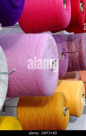 Verschiedene Spulen aus mehrfarbigen Wollfäden, abstrakter Hintergrund der Textilindustrie Stockfoto