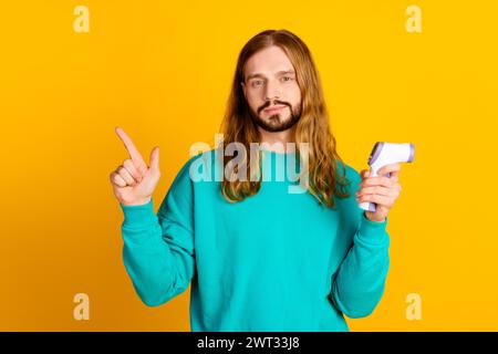 Porträt eines attraktiven Guy Hold Thermometers zeigt den leeren Finger auf gelbem Hintergrund Stockfoto