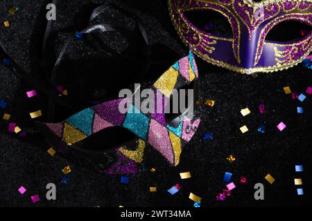 Nahaufnahme der Masquerade-Maske mit Konfetten auf schwarzem Hintergrund. Stockfoto