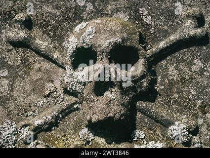 St. Andrew's Church, Hartburn, Morpeth, Northumberland. Schädel und Kreuzknochen auf der Tischgräber. Symbol der Sterblichkeit, des Todes und der Wiederauferstehung Christi. Stockfoto