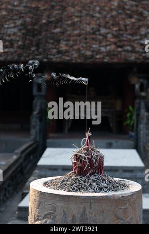 Eine Opfergabe von brennendem Weihrauch und Rauch, der in einem buddhistischen Tempel in Vietnam durch die Luft weht. Stockfoto