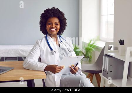 Porträt eines jungen afroamerikanischen Arztes in weißer medizinischer Uniform, der in die Kamera schaut. Stockfoto