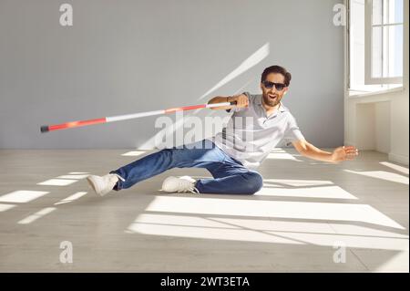 Blinder Mann mit Brille und Stock, der zu Boden fällt Stockfoto