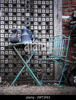 Rustikaler Eisentisch und -Stuhl Gartenmöbel in Hüttengarten mit Metallkrügen im Stil des Nahen Ostens Stockfoto
