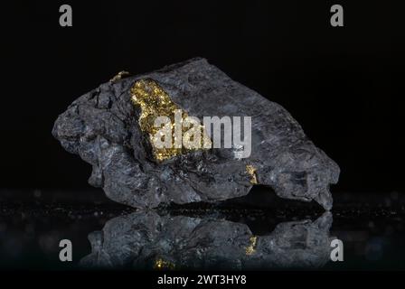 Ein Stück Goldnugget auf schwarzem Hintergrund mit Reflexion. Stockfoto