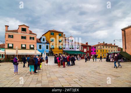 Burano, Italien - 6. Oktober 2019: Touristen in der Nähe der Statue von Baldassare Galuppi auf dem Hauptplatz von Burano, der Piazza Galuppi. Helle traditionelle farbenfrohe Gebäude auf der Insel Burano, Venedig, Italien. Stockfoto