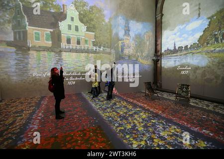 Ein Besucher mit einer Maske zum Schutz vor COVID-19 fotografiert ein Gemälde von Claude Monet, das an die Wand projiziert wurde, in der Ausstellung „Monet: T Stockfoto