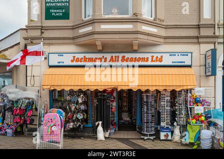 Jackman's All Seasons Ltd. Vordereingang des Souvenirshops in Teignmouth, Devon, England, Großbritannien. Artikel zum Verkauf in Regalen und auf dem Gehweg gestapelt. Stockfoto