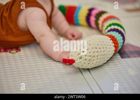 Das Baby spielt mit einem gestrickten Spielzeug im Kinderzimmer Stockfoto