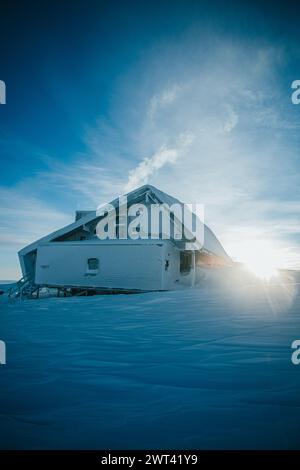 Eine Winterszene mit einem Haus im Schnee, die Sonne scheint Stockfoto