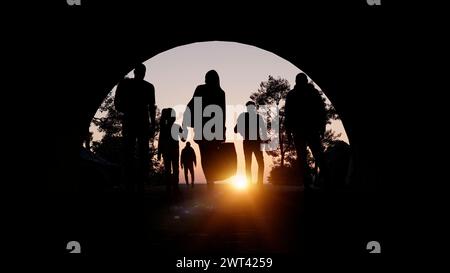 Flüchtlinge und Immigranten, die eine neue Hoffnung im Leben suchen. Silhouette. Kolonne von Migranten, die durch einen Tunnel fahren. Ihr Land verlassen Stockfoto