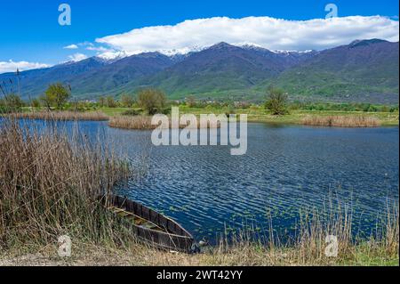 Blick auf Kerkini See im Norden Griechenlands ist mit traditionellen Holzmöbeln Fischerboot und Teil des schneebedeckten Mount Beles Stockfoto