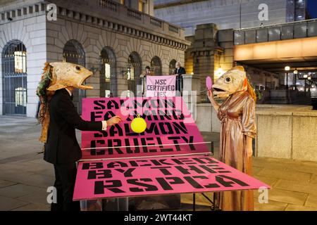 26. Oktober 2023, Fishmongers Hall, London, Großbritannien. Ozeanaufstand protestiert gegen ökologische Schäden durch Lachszucht. In der Halle veranstaltet der Marine Stewardship Council sein Annual Awards Dinner. Pressemitteilung: Am Donnerstag, den 26. Oktober, um 18:00 Uhr starteten zwei Lachsdarsteller von Ocean Rebellion vor dem Annual Awards Dinner des Marine Stewardship Council in der Fishmongers’ Hall am Ufer der verschmutzten Themse in London. Sie trugen groteske Lachsköpfe und begannen sofort ein skurriles und SKRUPELLOSES Spiel mit ROSA PONG, was die schreckliche Grausamkeit des schottischen salms hervorhob Stockfoto