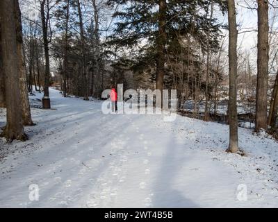 Frau, die im Winter am West River, Riviere del’Ouest, Brownsburg-Chatham, Quebec, Kanada, läuft, Stockfoto