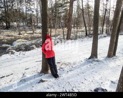 Während der COVID-Epidemie stand eine Frau mit Maske im Park im Winter neben West River, Brownsburg-Chatham, Quebec, Kanada, Stockfoto