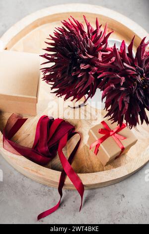 Zwei schwarze Dahlienblumen, Geschenkkartons mit rotem Band. Stockfoto