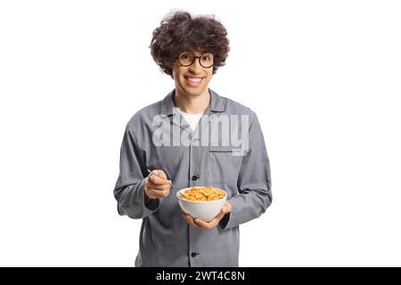 Junger Mann im Pyjama, der eine Schüssel mit Knollenflocken auf weißem Hintergrund hält Stockfoto