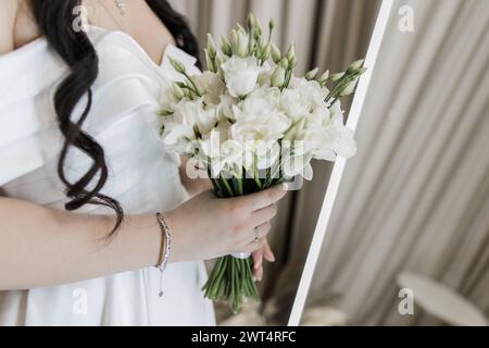 Der zarte Griff einer Braut auf elegantes weißes Bouquet Stockfoto