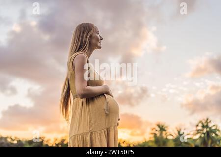 Ruhige Szene, in der eine schwangere Frau friedliche Momente im Park genießt, die Ruhe der Natur genießt und während ihrer Schwangerschaft Trost findet Stockfoto